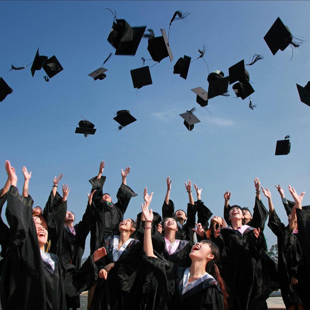 Group of people throwing graduation caps in the air.